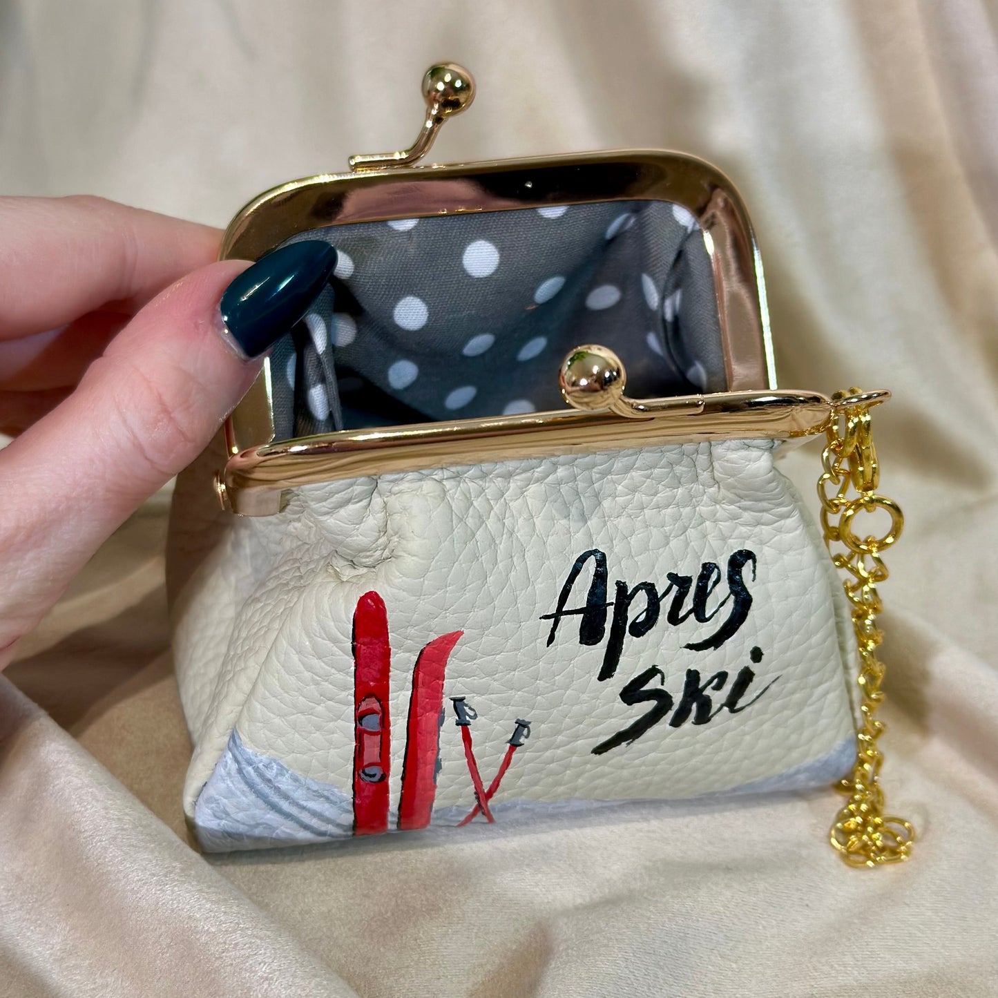 Handbag with 'Apris Ski' design held by a hand on a beige background