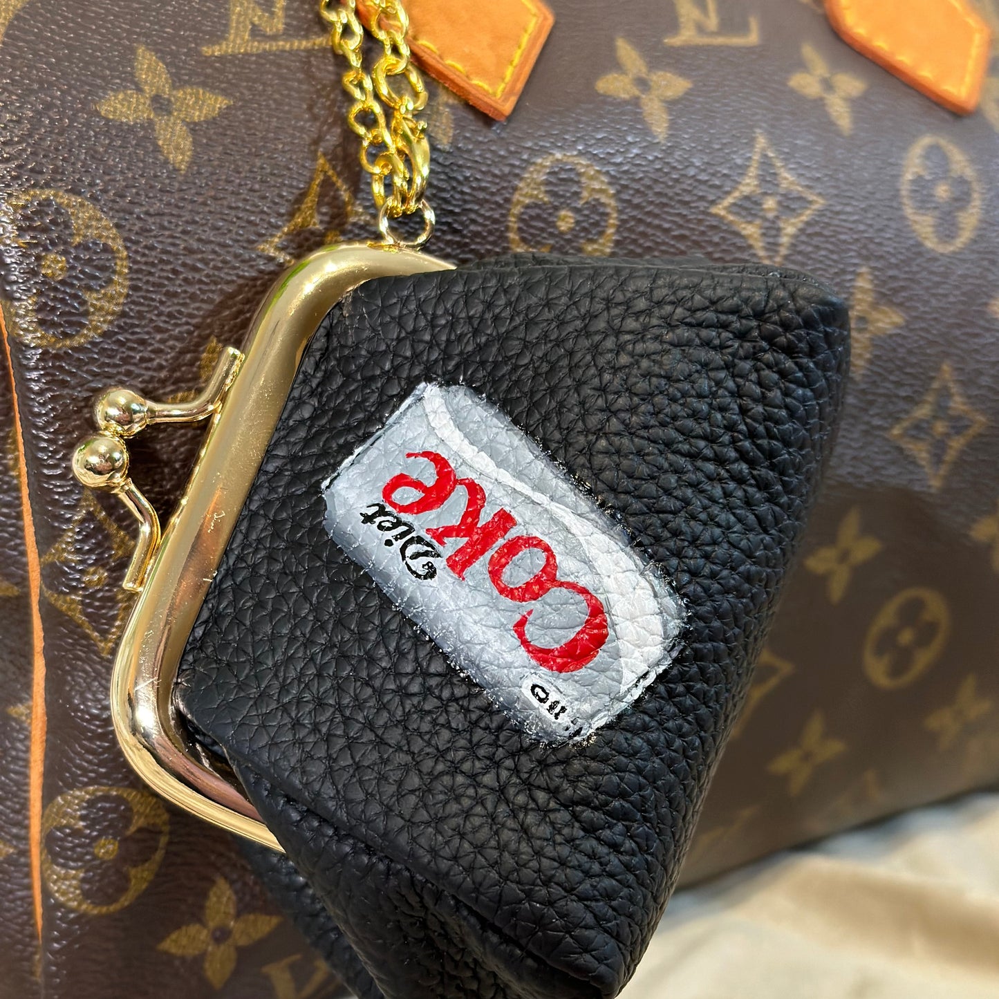 Black handbag with a Coca-Cola patch on a patterned surface