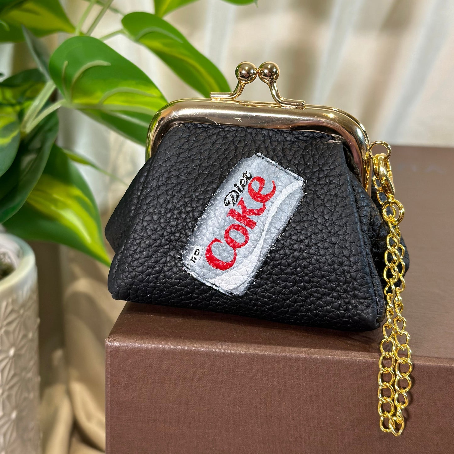 Black coin purse with a visible brand logo on a neutral background
