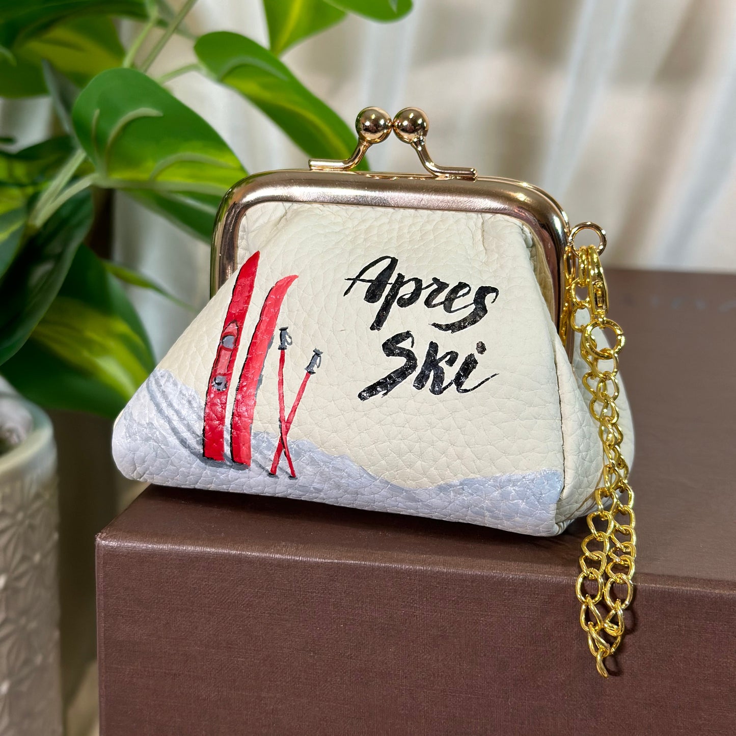 Small embroidered bag with 'Apres Ski' text and red ski design on a blurred background