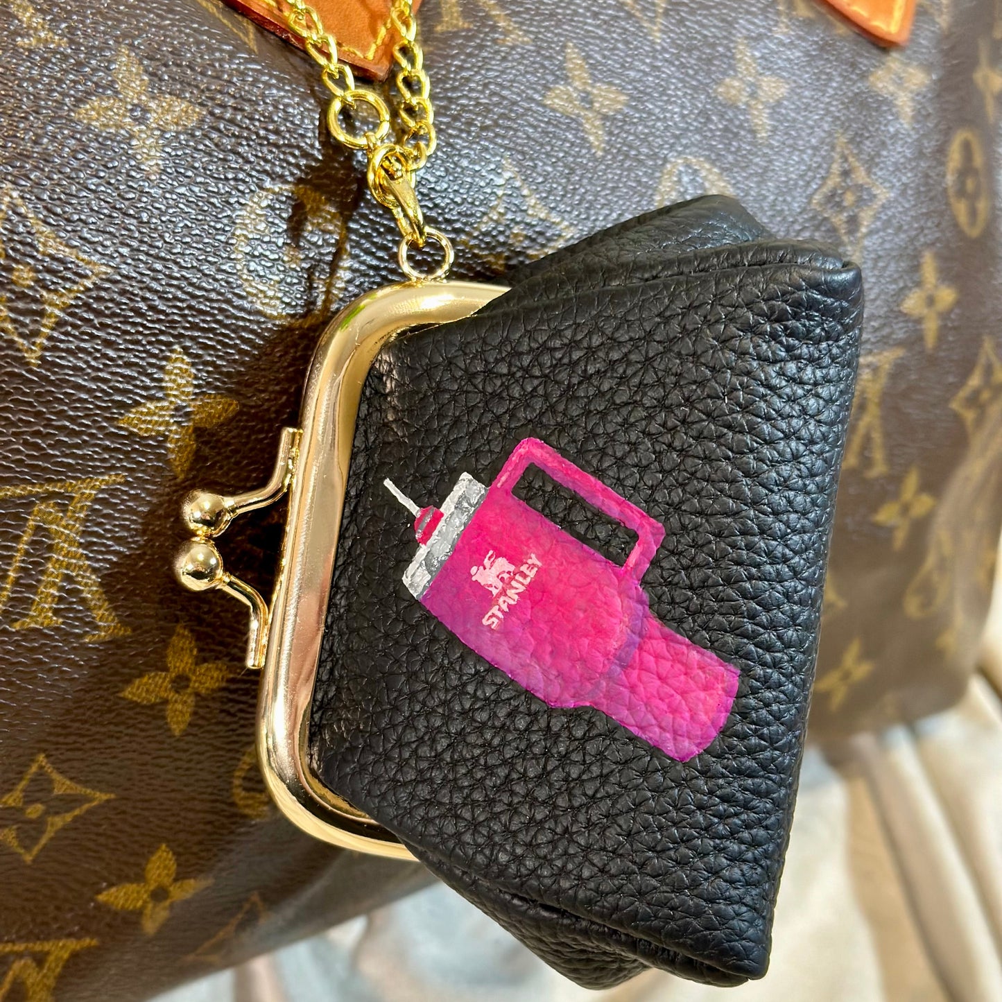 Black purse with pink and white design on a patterned surface