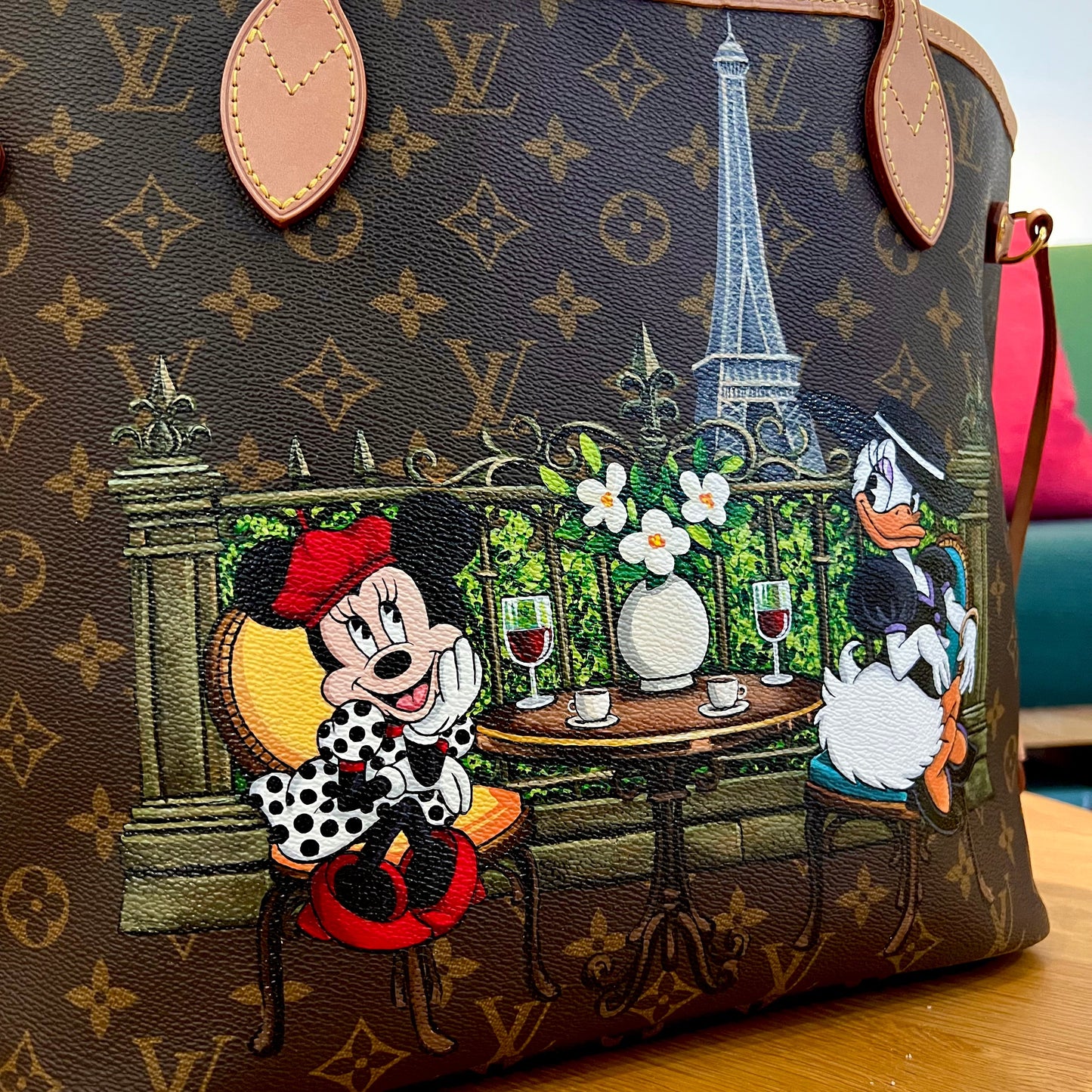 Designer handbag with cartoon characters and Eiffel Tower design on a wooden surface