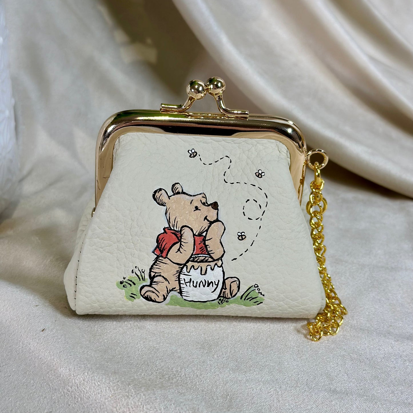 Small white purse with a cartoon character and gold chain on a light background