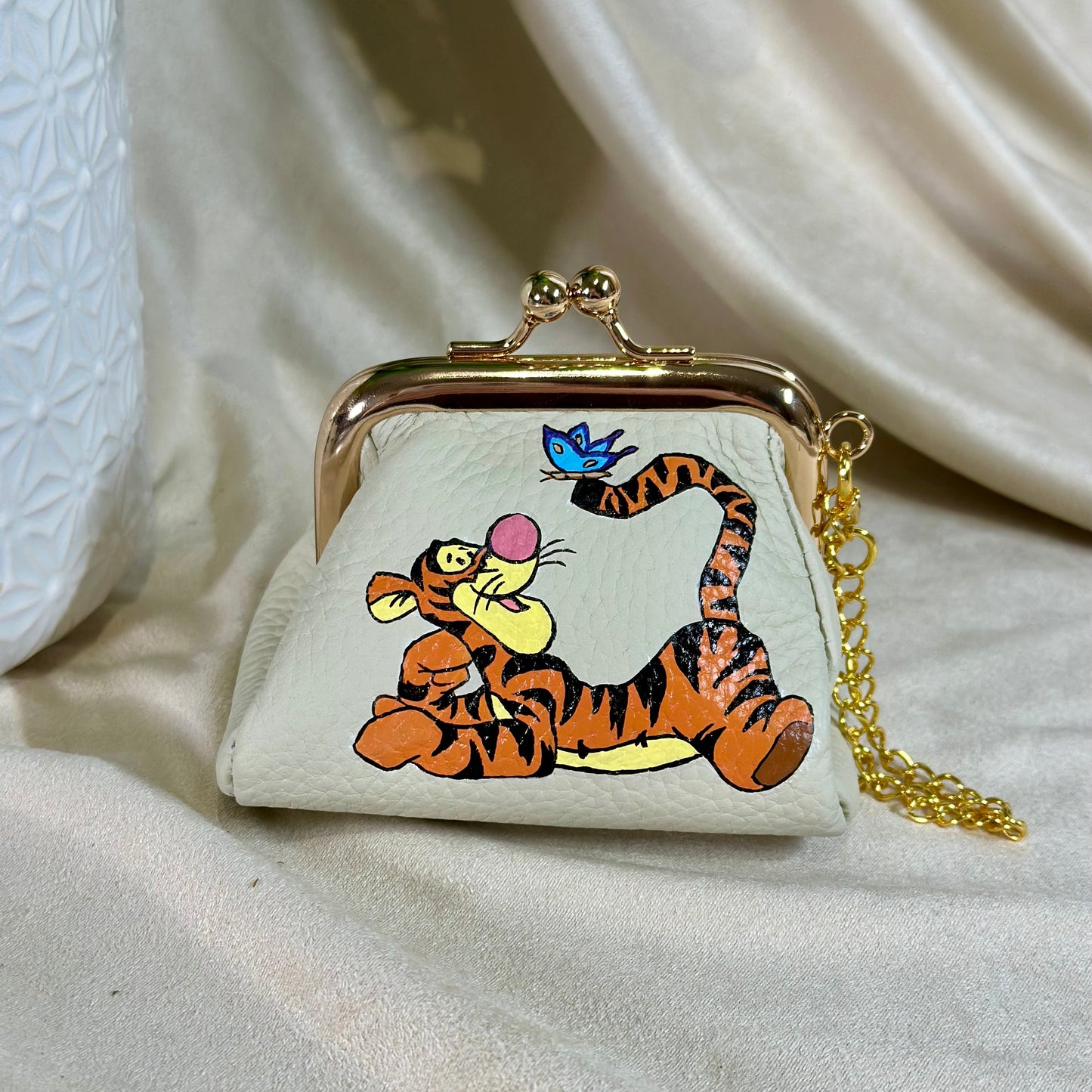 Small purse with cartoon tiger design on a beige fabric background