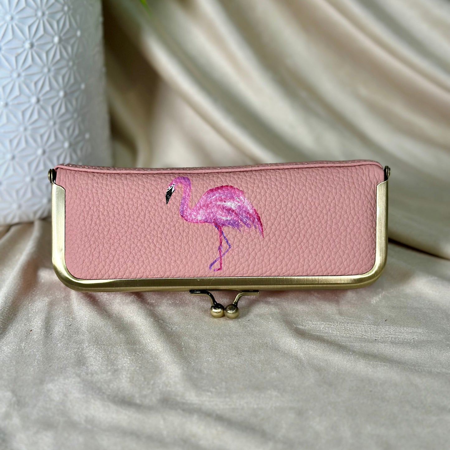 Pink clutch with flamingo design on a light surface