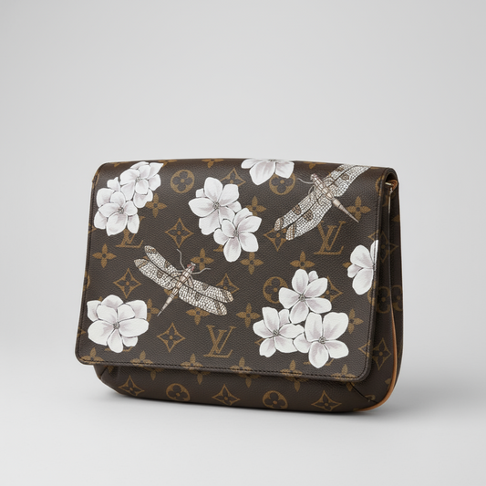 Designer handbag with floral and dragonfly pattern on a surface