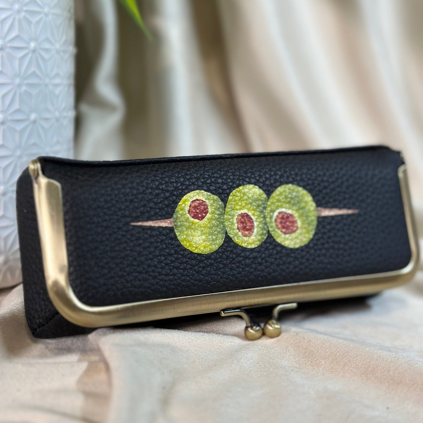 Black clutch with green and red design on a light background