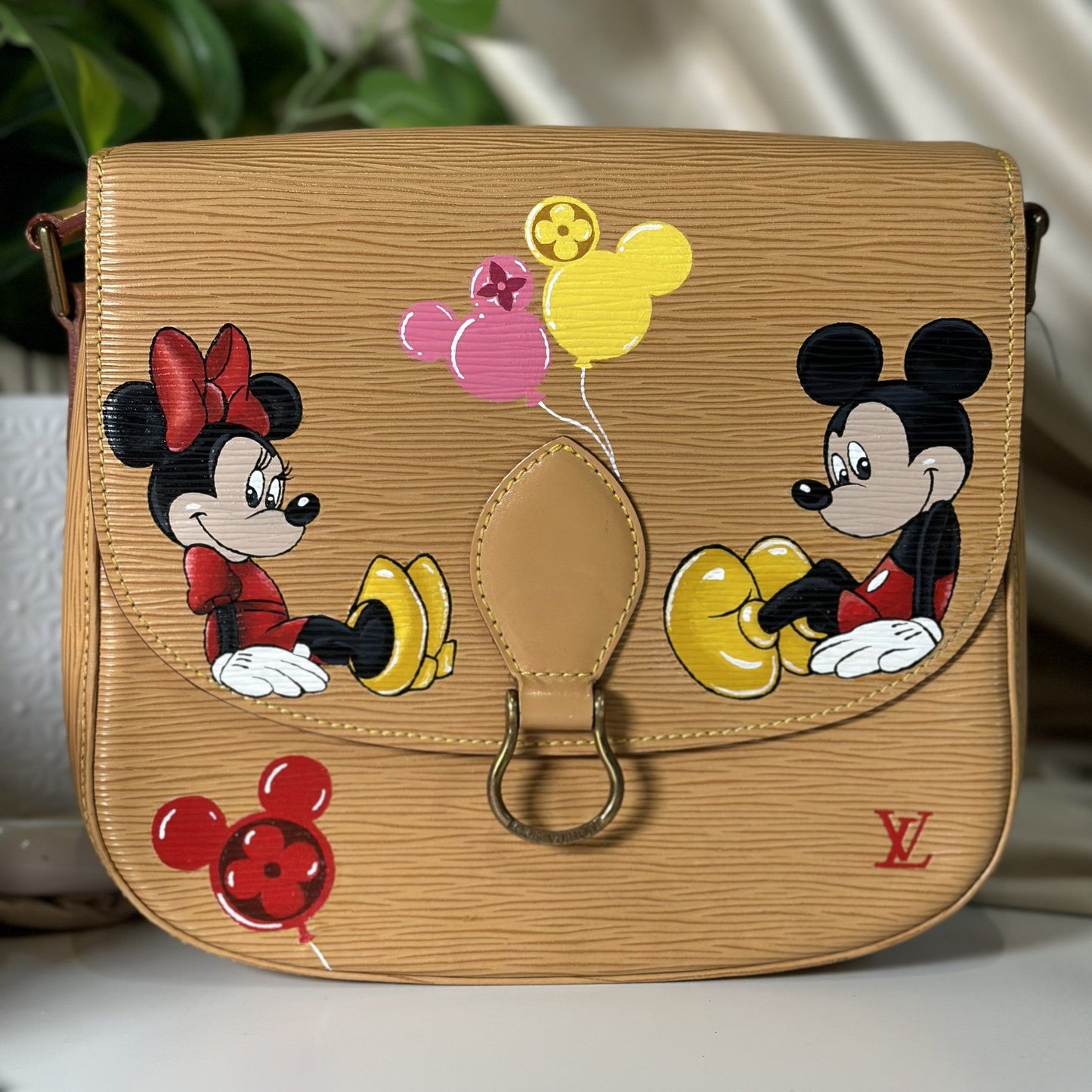 Designer handbag with cartoon characters and balloons on a neutral background