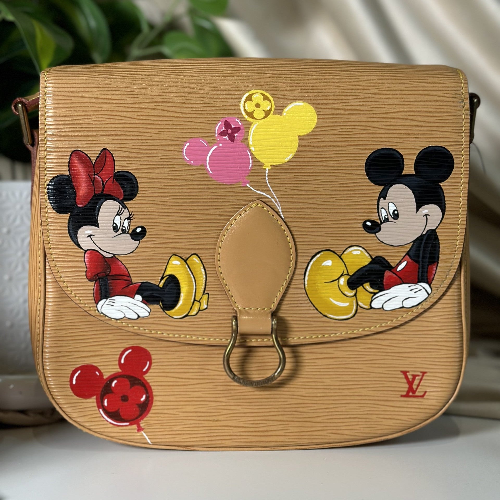 Designer handbag with cartoon characters and balloons on a neutral background