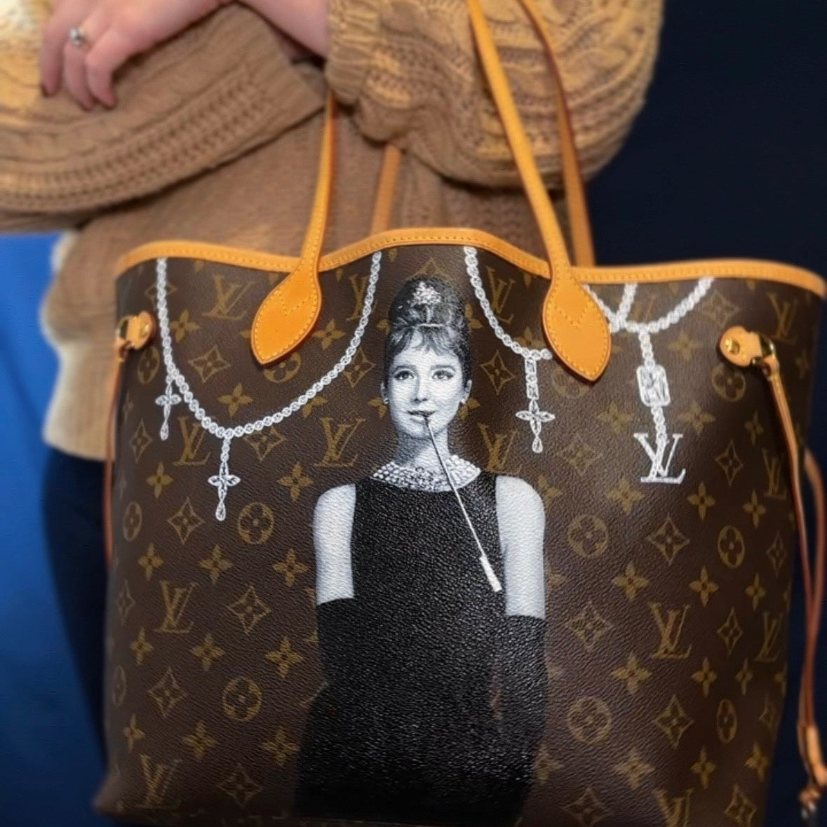 Designer handbag with a graphic design of a woman on a dark background