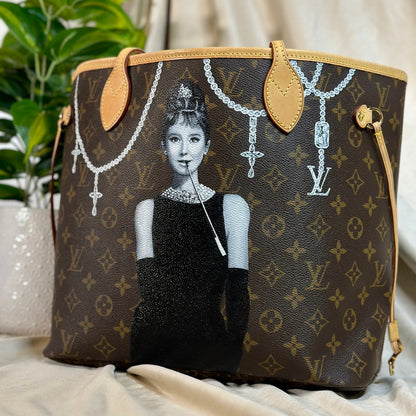 Designer handbag with artistic depiction of a woman wearing jewelry on a neutral background