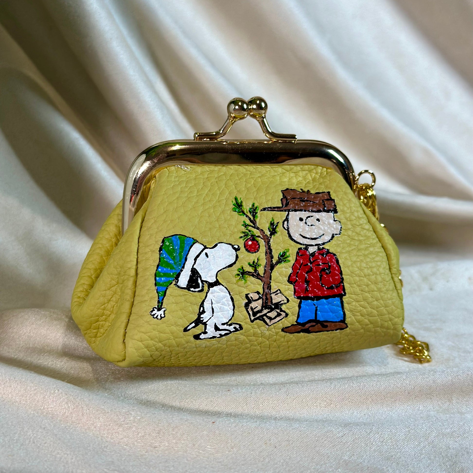 Small yellow purse with embroidered design of cartoon characters on a white fabric background