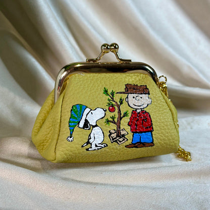 Small yellow purse with embroidered design of cartoon characters on a white fabric background
