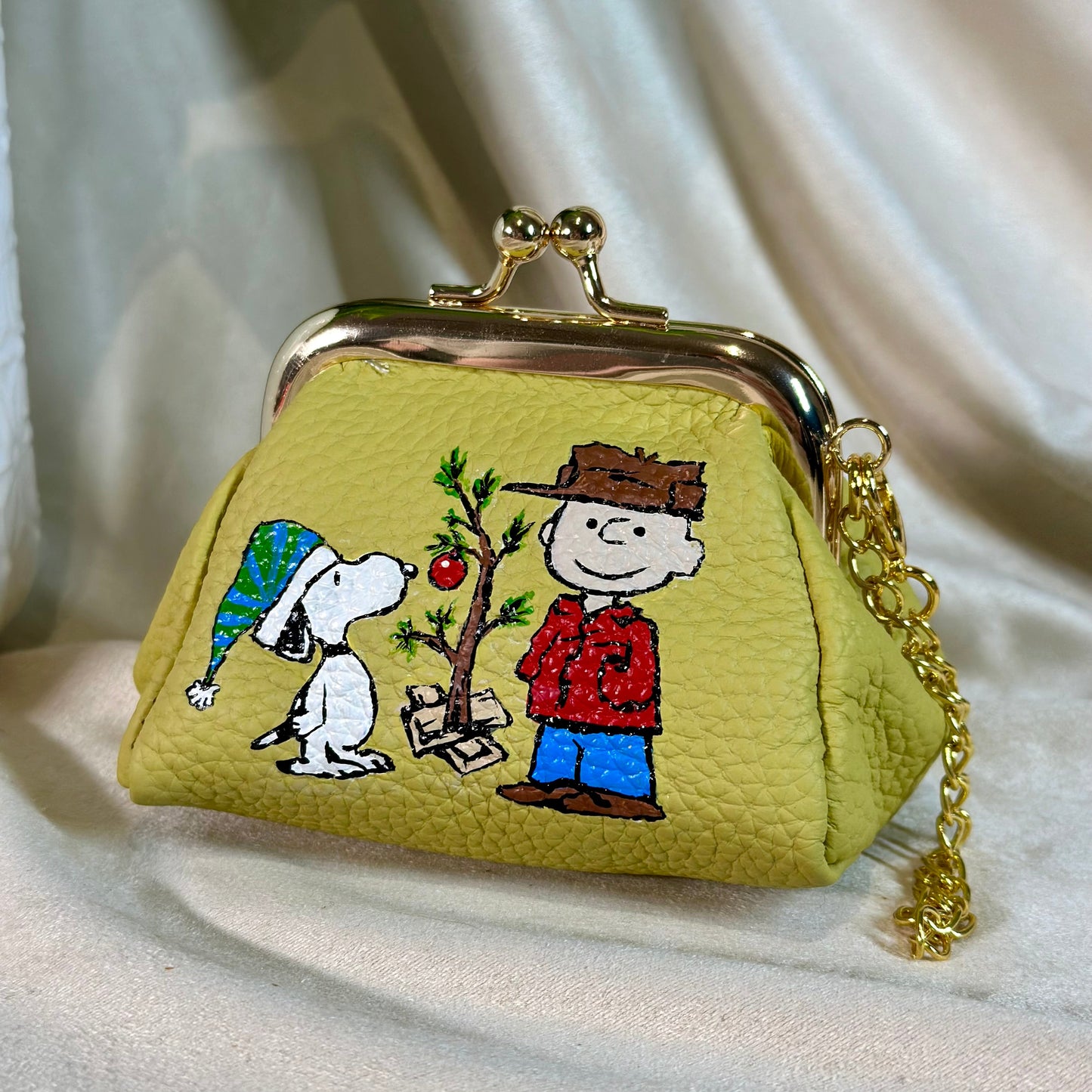 Small green purse with cartoon characters on a white fabric background