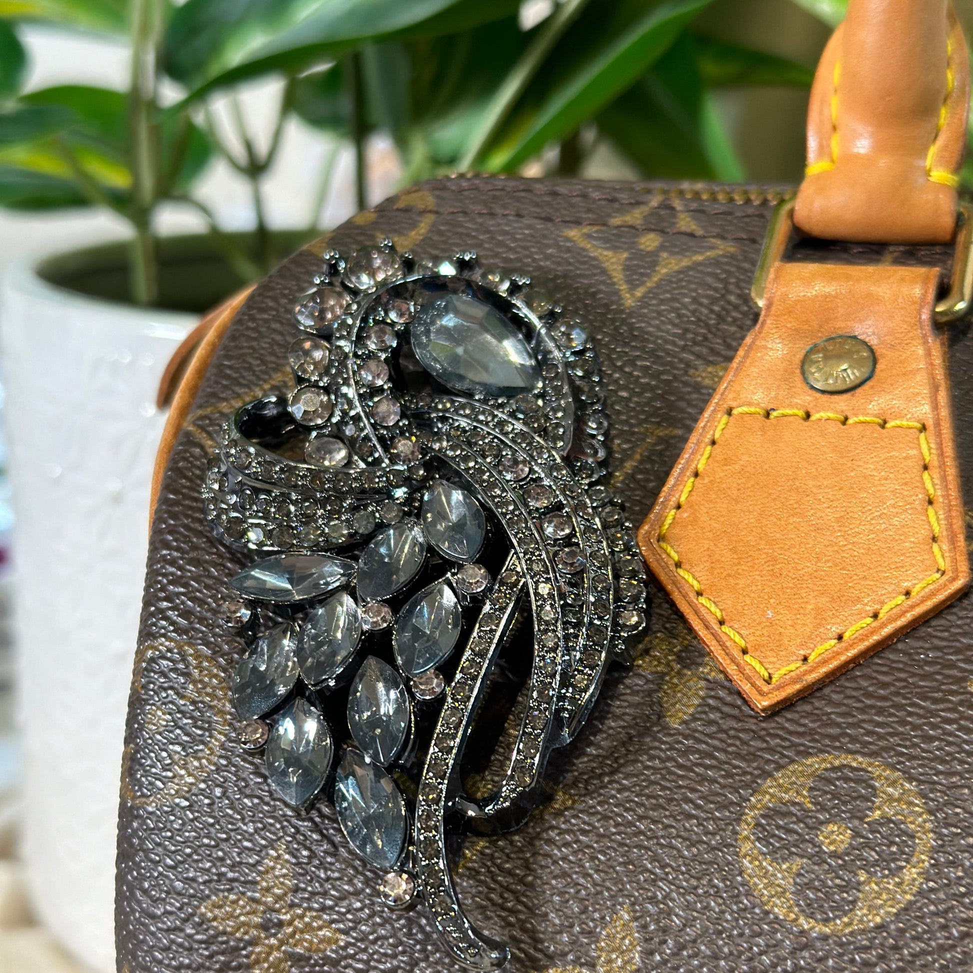 Decorative brooch on a Louis Vuitton handbag with a blurred background