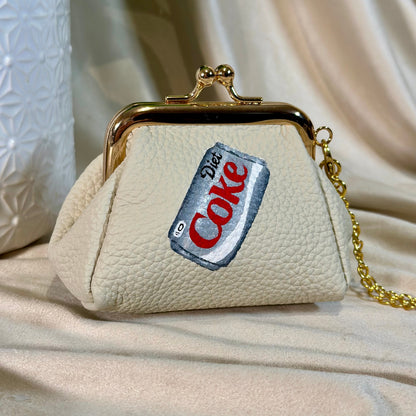Beige handbag with a Diet Coke label patch on a beige fabric background