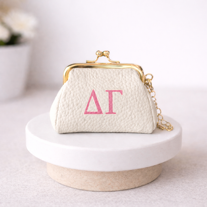 Small white handbag with gold clasp and pink letters on a white surface