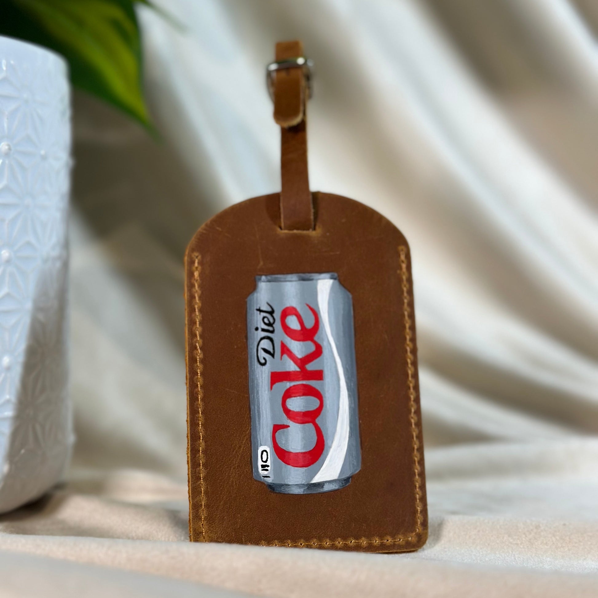 A hand painted Diet coke painted onto a luggage tag.