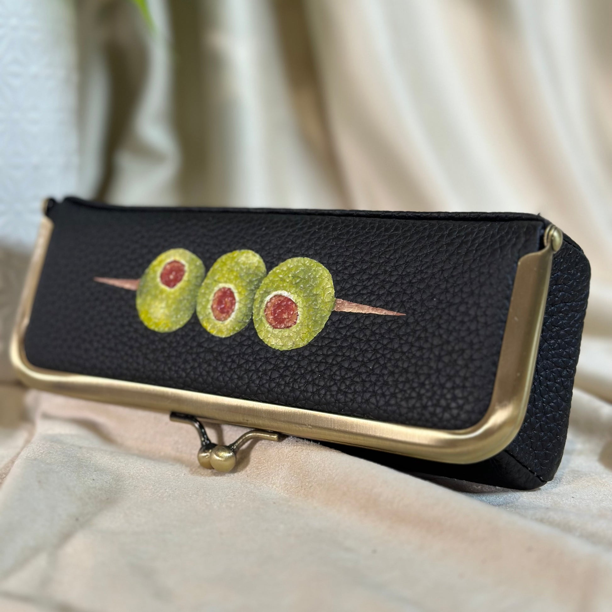 Black pouch with avocado design on a light fabric background