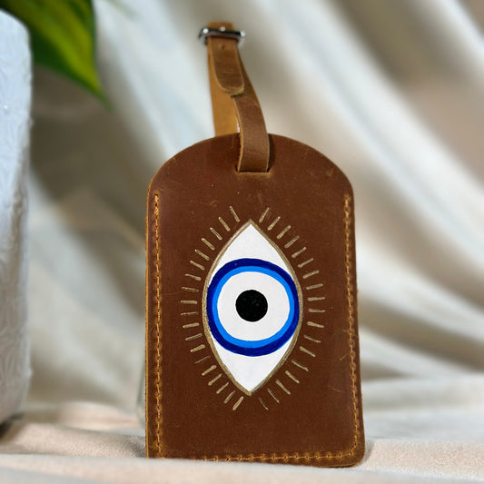 Brown luggage tag painted with an evil eye