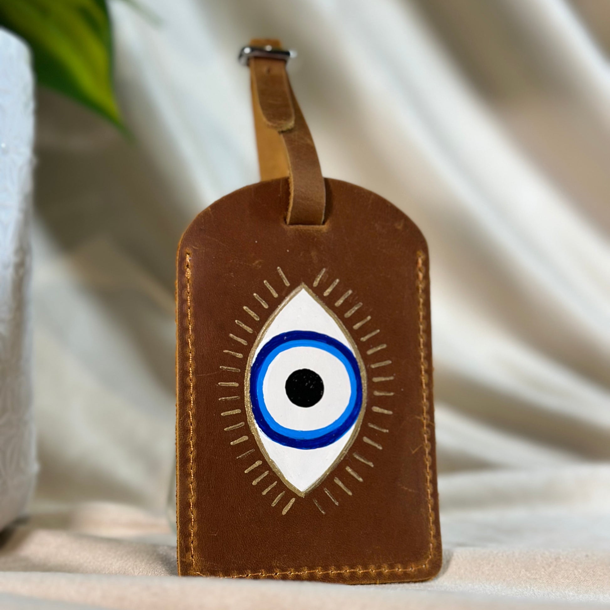 Brown leather luggage tag with an eye design on a light background