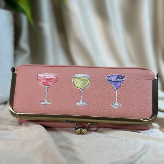 Pink wallet with wine glass illustrations on a light fabric background