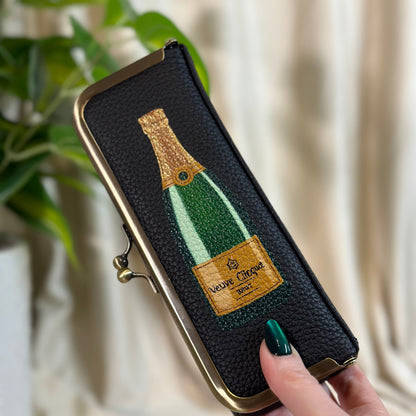 Phone case with champagne bottle design held by a hand against a neutral background