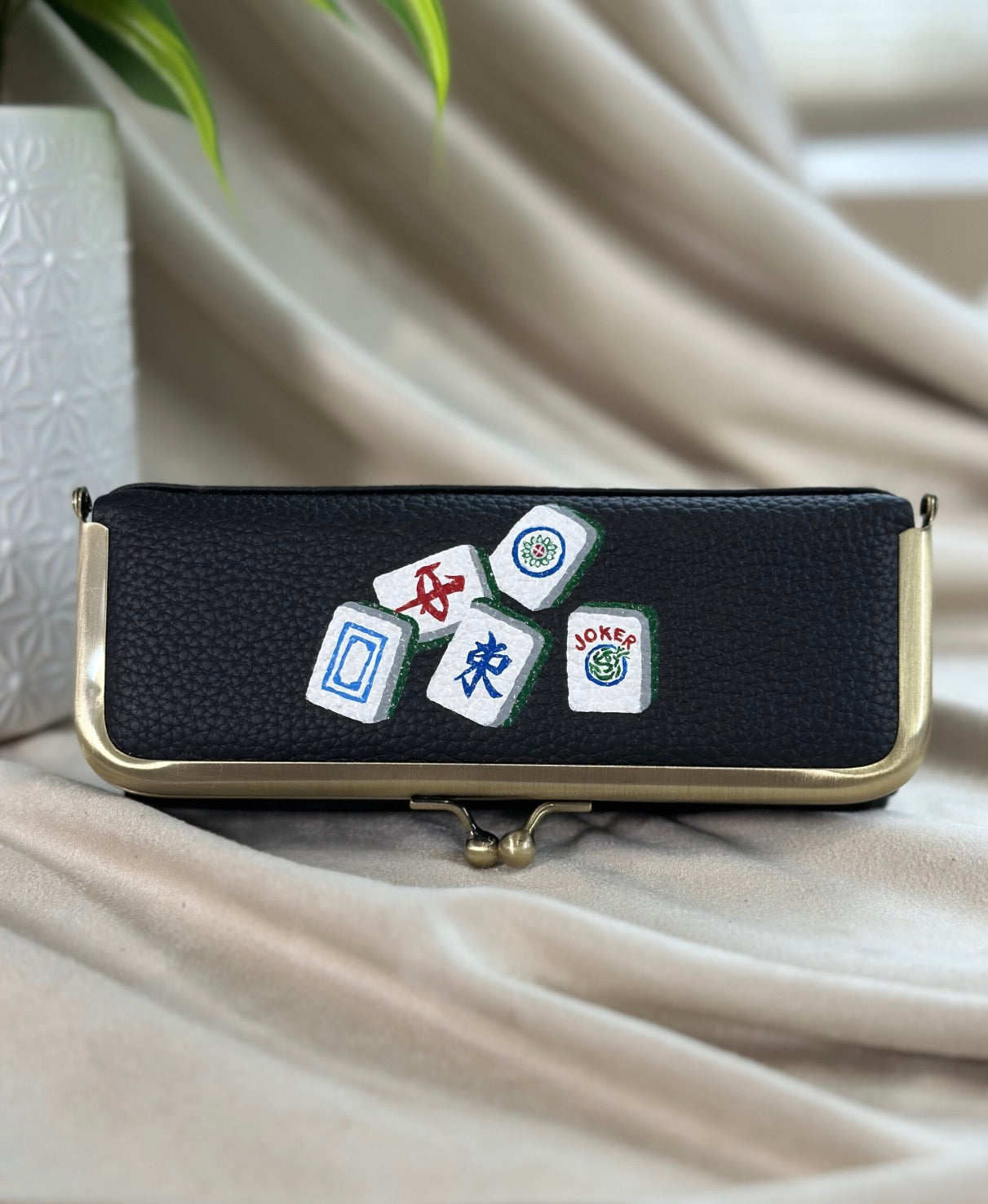 Black pouch with dice and card game symbols on a beige fabric background