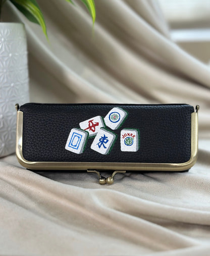 Black pouch with dice and card game symbols on a beige fabric background