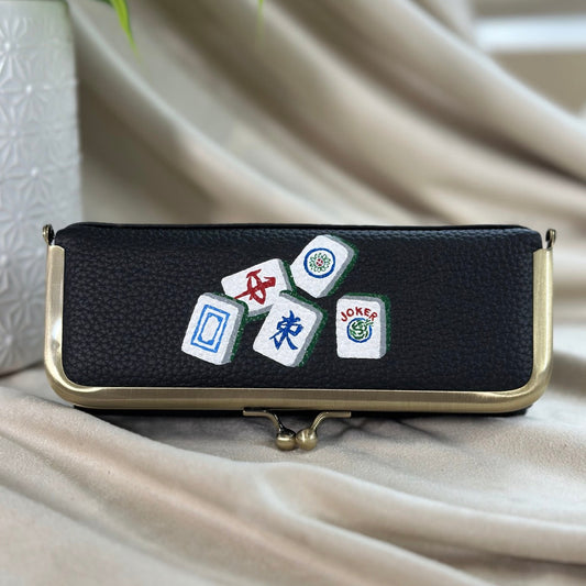 Black pouch with dice and card game symbols on a beige fabric background