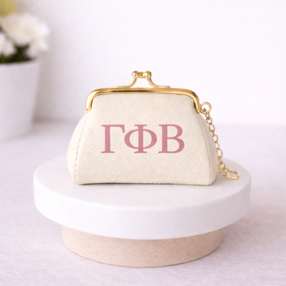 Beige clutch bag with pink Greek letters on a white surface