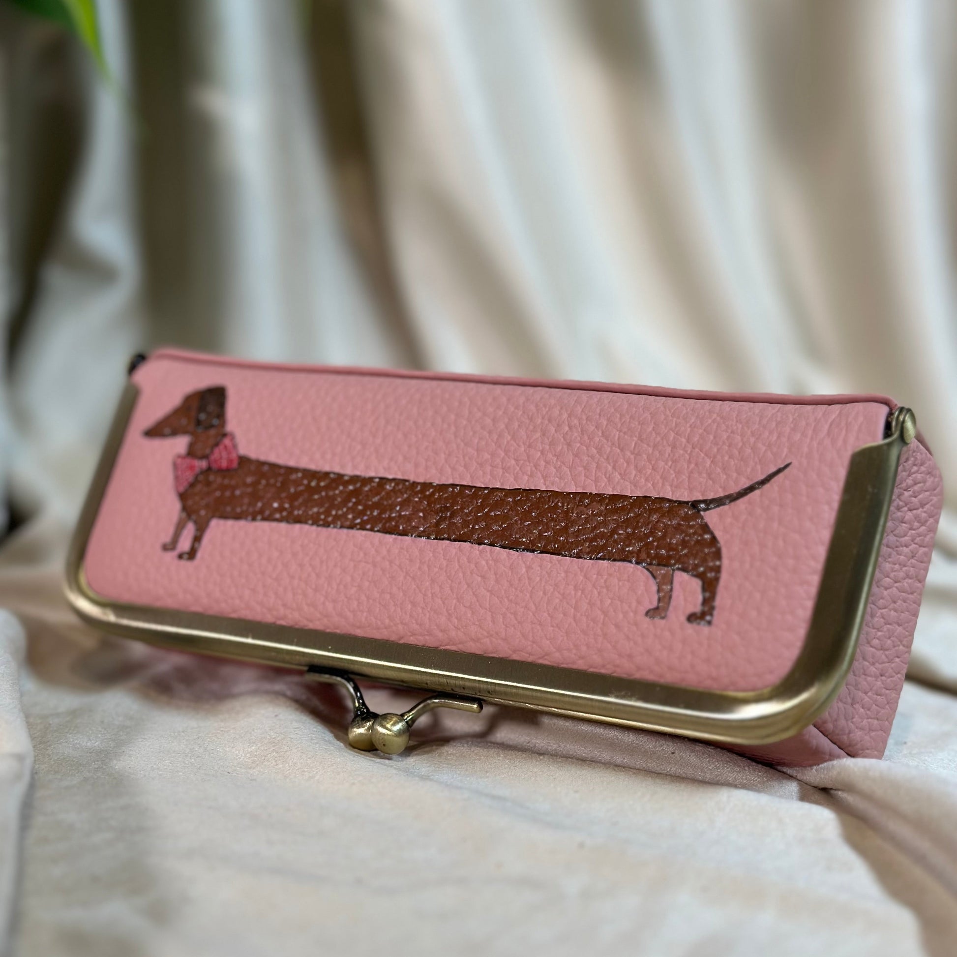 Pink wallet with dachshund design on a light fabric background