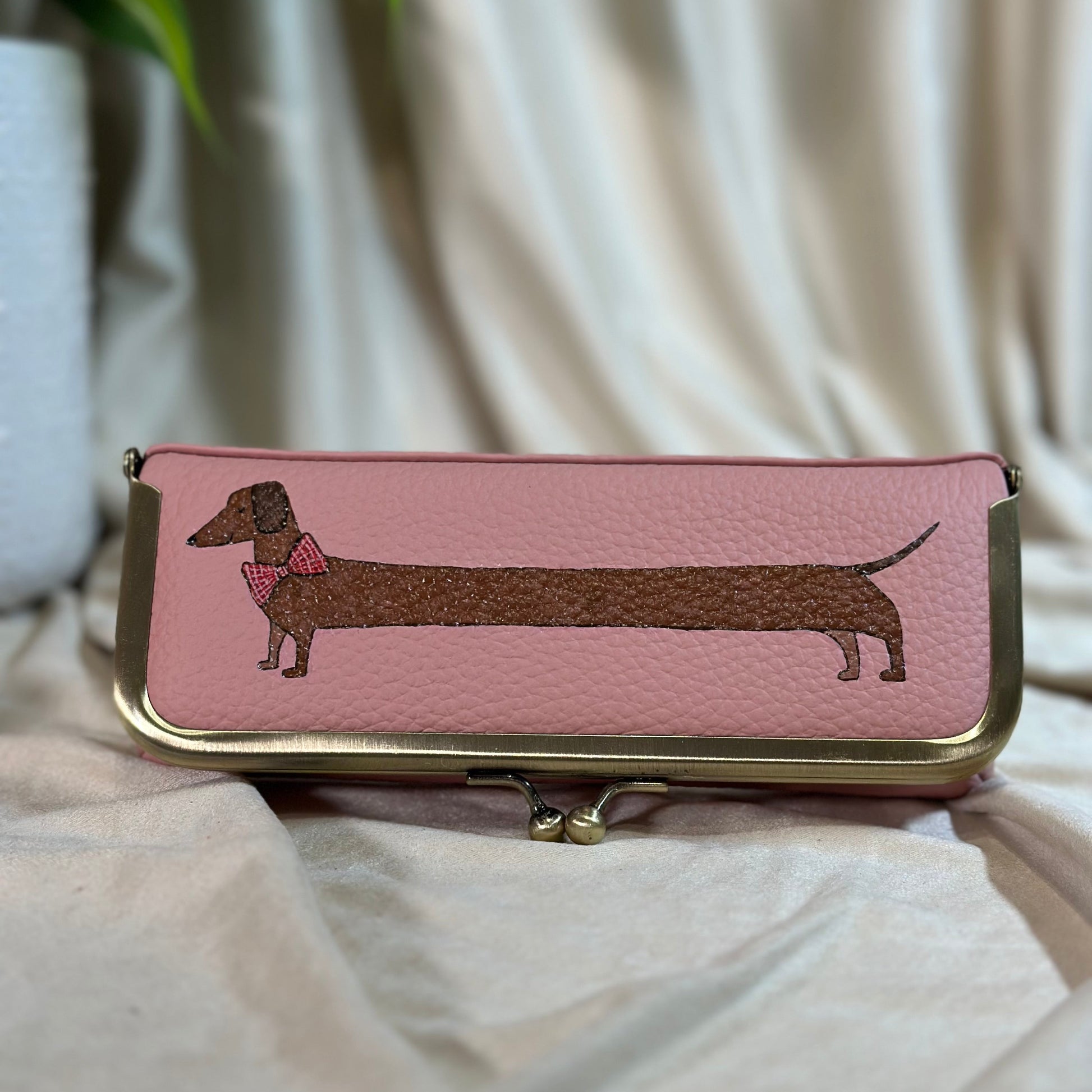 Pink wallet with dachshund design on a light fabric background
