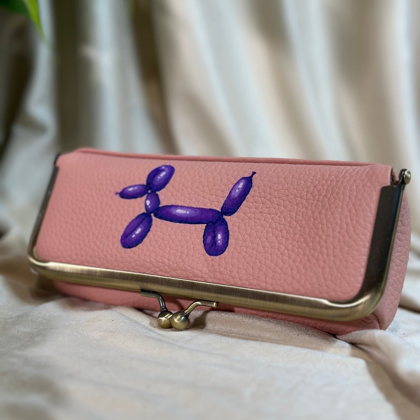 Pink handbag with a purple balloon dog design on a light background