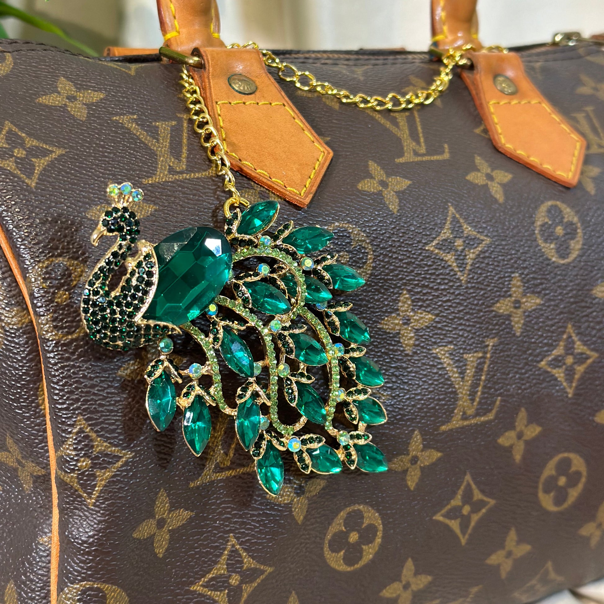 Green peacock brooch on a patterned handbag