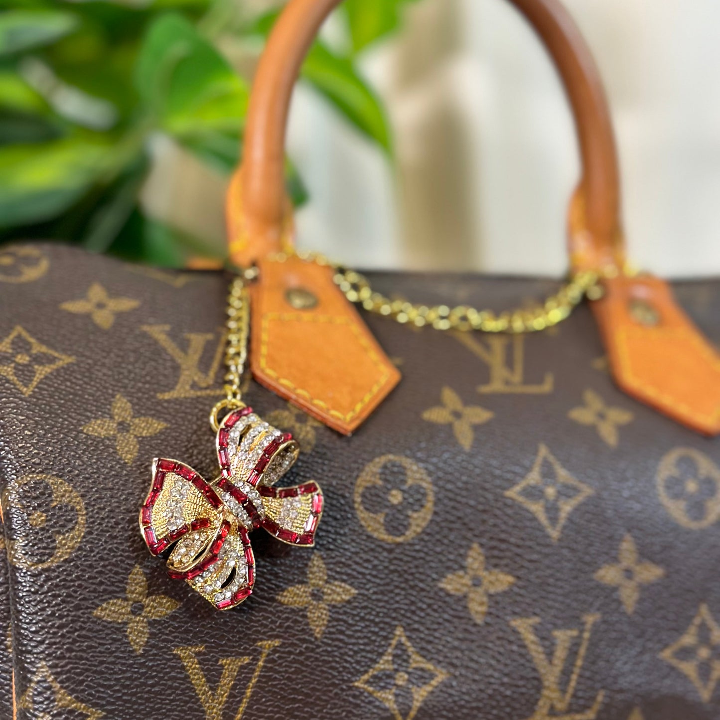 Louis Vuitton handbag with a decorative keychain featuring a red and gold bow.