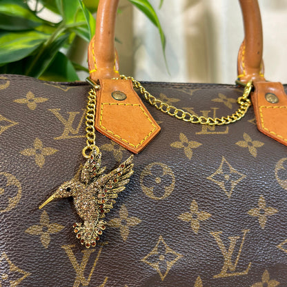 Louis Vuitton handbag with a decorative charm on a blurred background