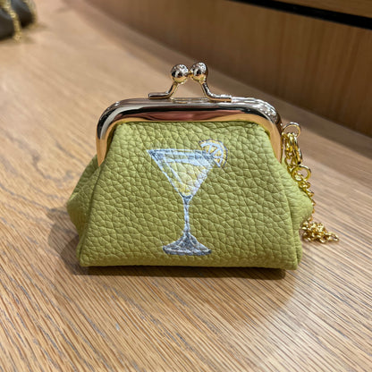 Green textured coin purse with a drink illustration on a wooden surface