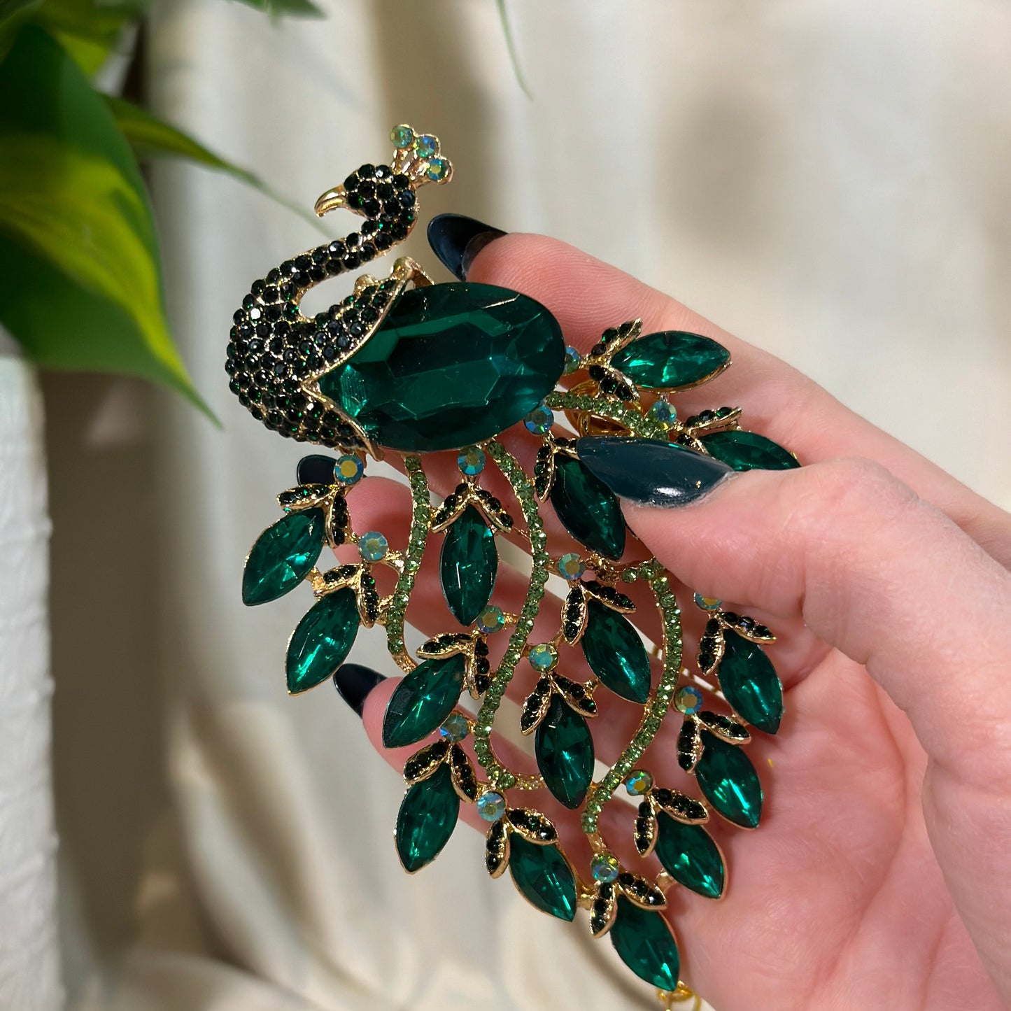 Jewelry with green gemstones held in a hand against a neutral background