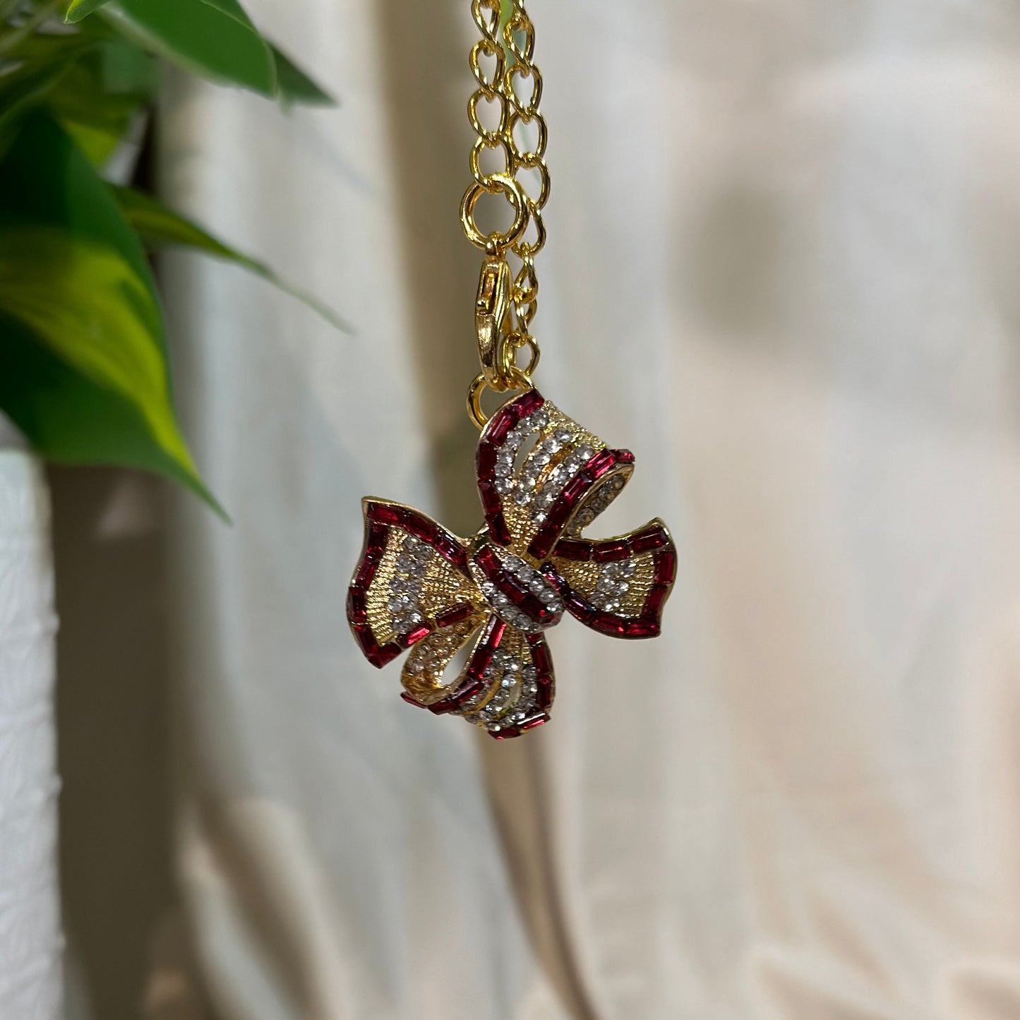 Gold necklace with a decorative bow pendant on a light fabric background