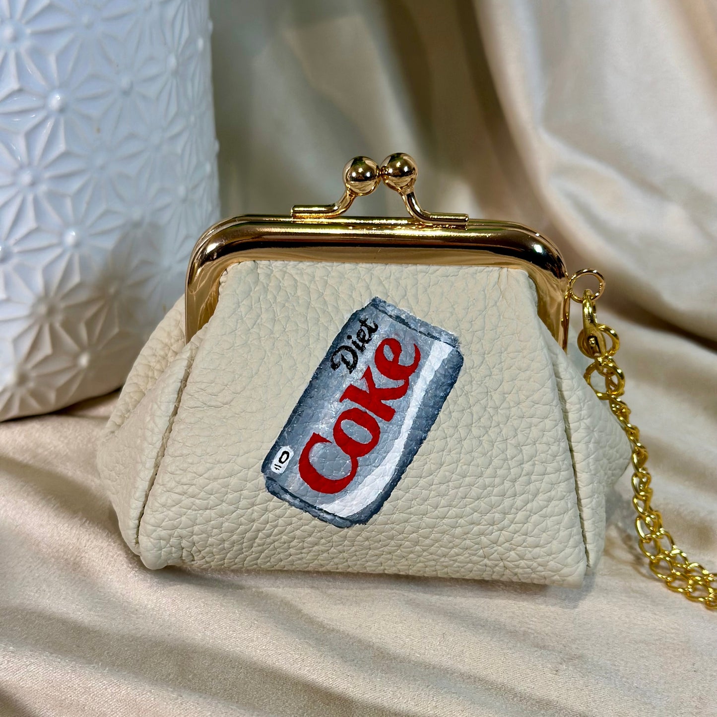 Beige handbag with a 'Diet Coke' label on a beige fabric background