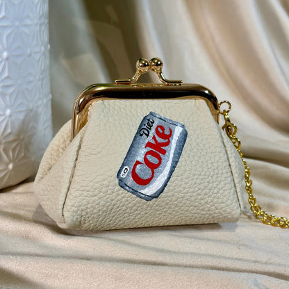 Beige handbag with a Diet Coke label patch on a beige fabric background