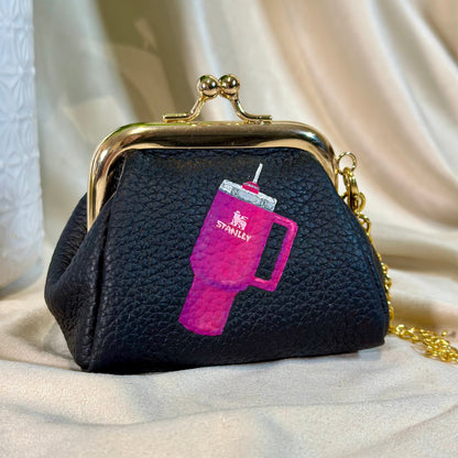 Black purse with pink Stanley logo on a beige fabric background