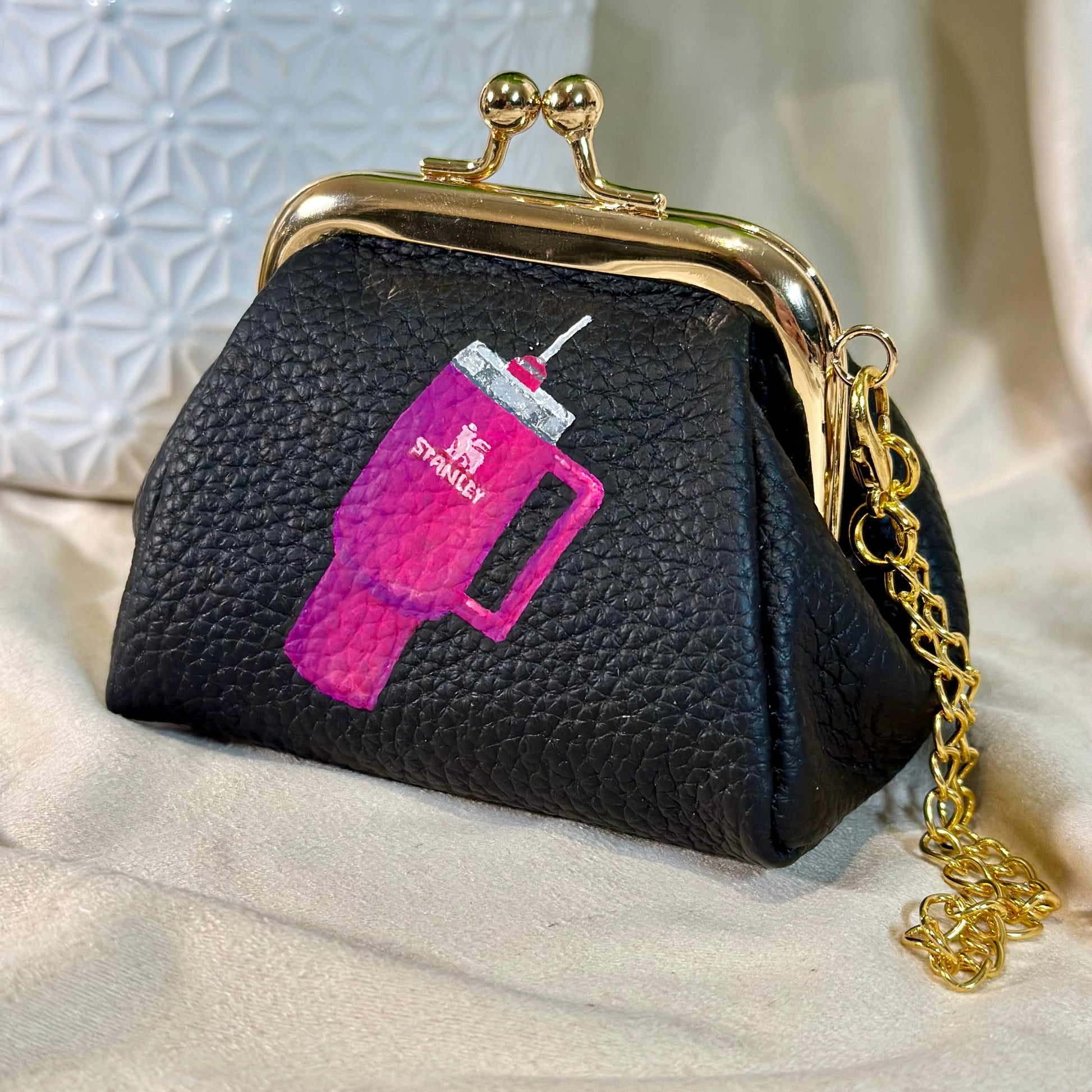 Black purse with pink and white design on a light background