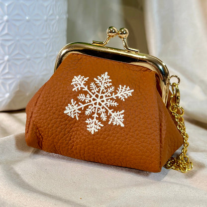 Brown purse with a white snowflake design on a light background