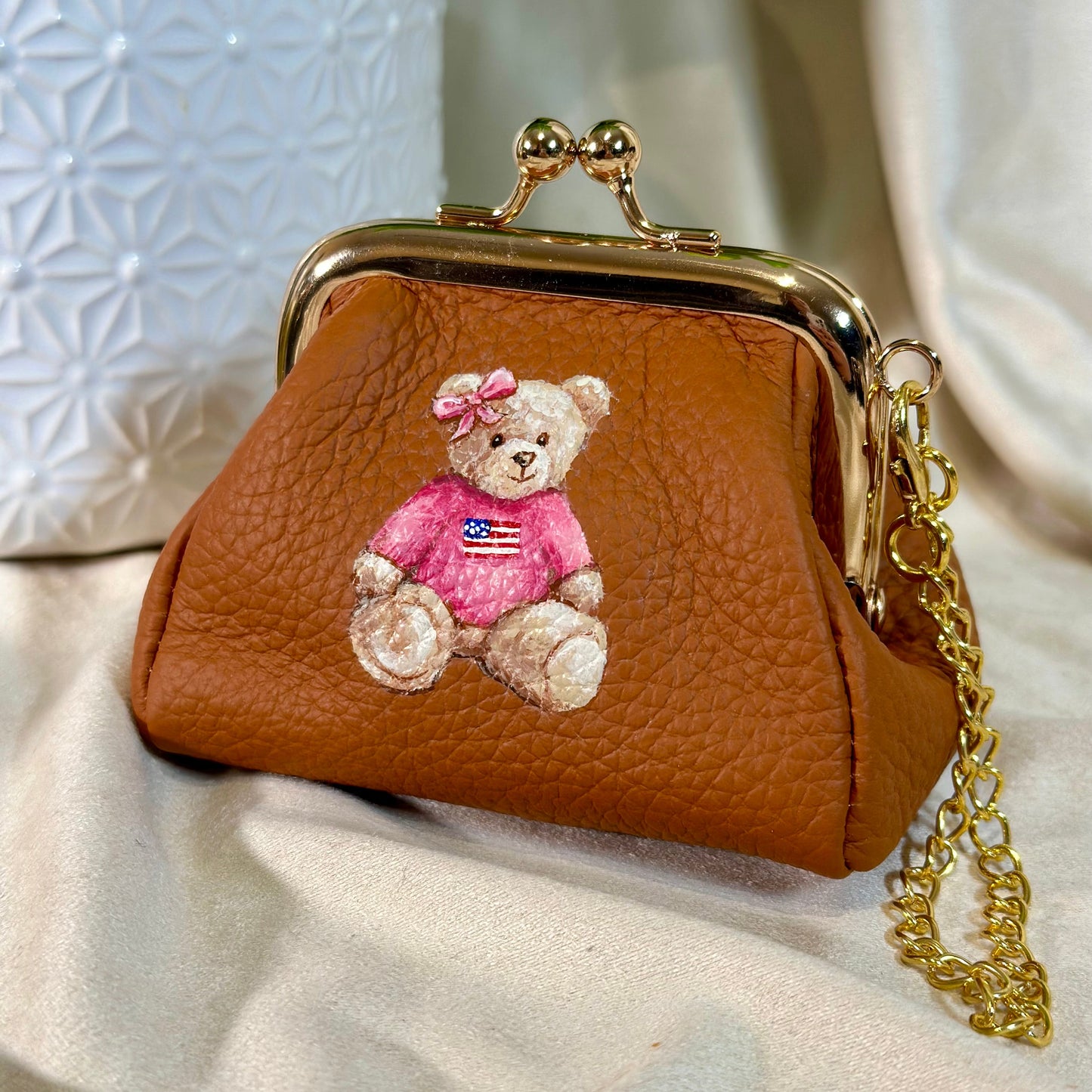 Brown leather coin purse with teddy bear design on a light fabric background