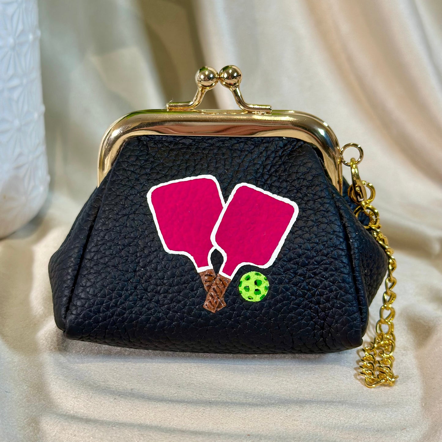 Black purse with pink pickleball paddle design on a beige background