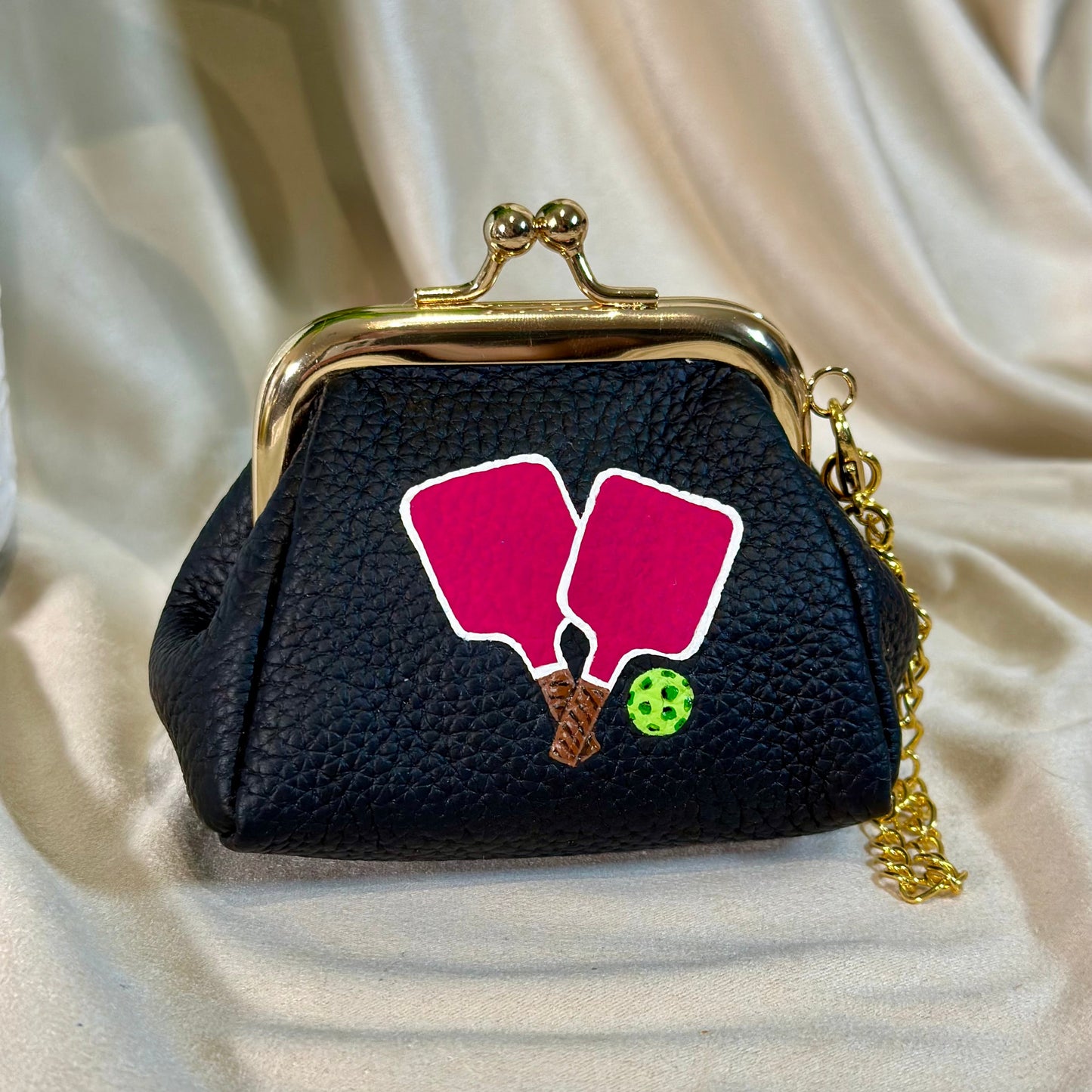 Black textured purse with pink floral design on a beige fabric background