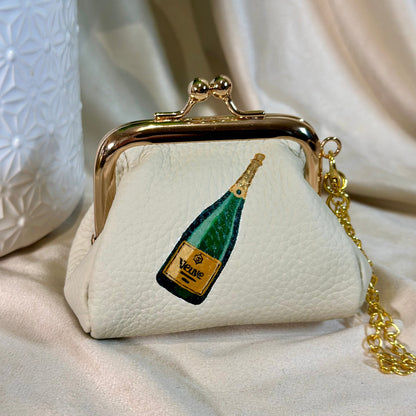 Small white handbag with a champagne bottle design on a beige surface