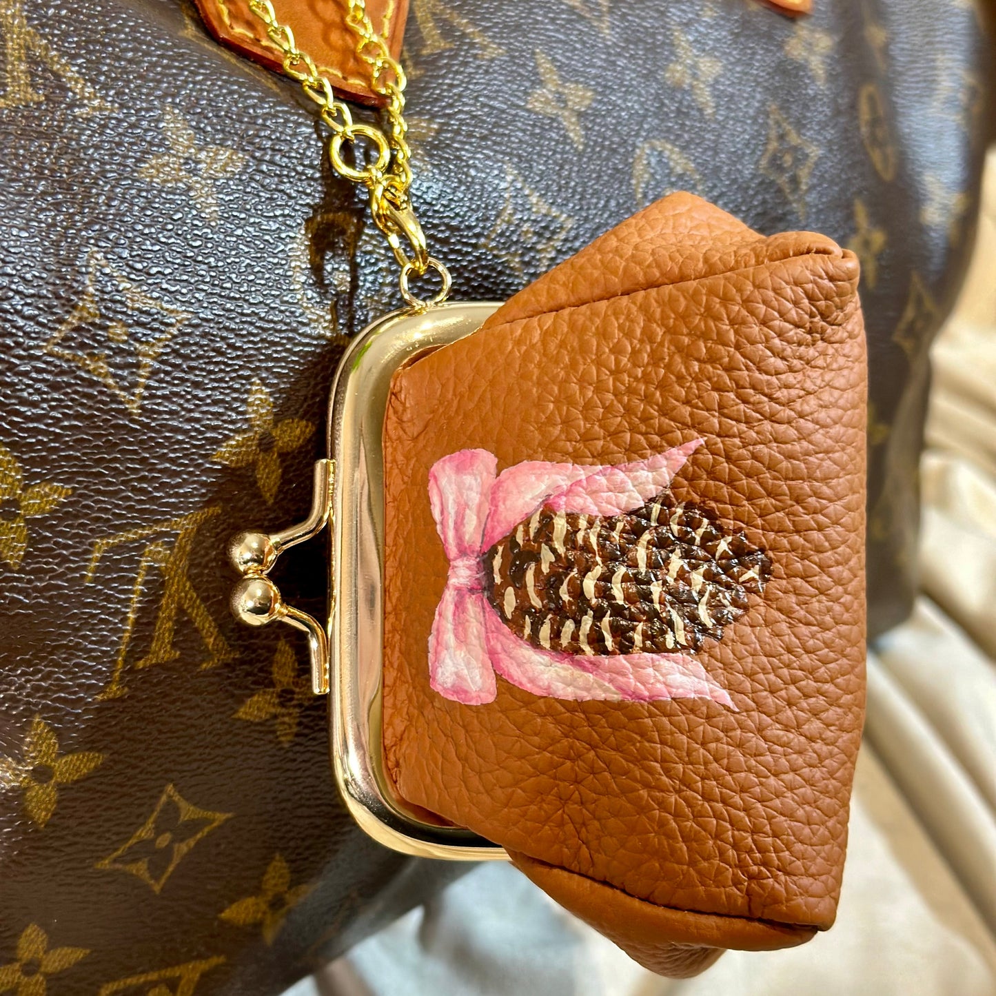 Brown leather pouch with floral design in front of a patterned handbag